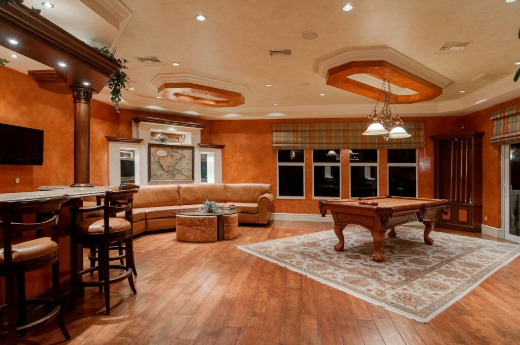 billiard table in center of brown painted room with laminate flooring