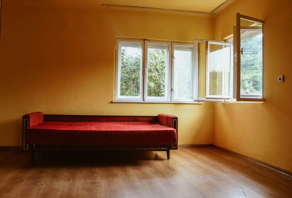 red padded sofa on laminate flooring beside window