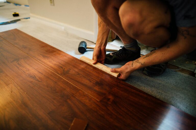 Crop man installing laminate flooring over underfloor heating