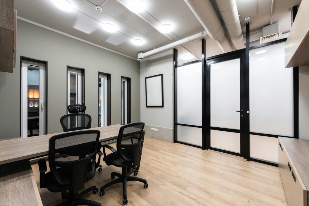 Wooden table and black office chairs placed in spacious room on 8mm laminate flooring