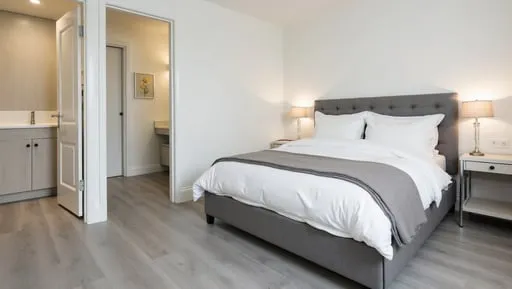 A_modern_bedroom_with_waterproof_grey_laminate_flooring_flowing